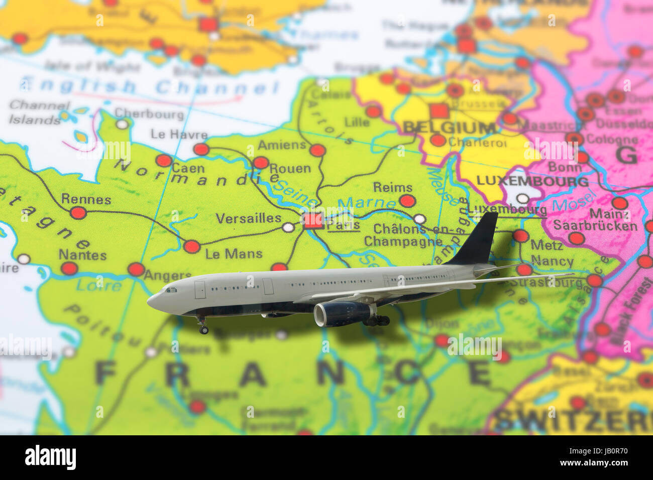 Paris in France pinned aircraft travelling on colorful political map of Europe. Geopolitical school atlas. Holidays and travel concept. Flights to Eur Stock Photo