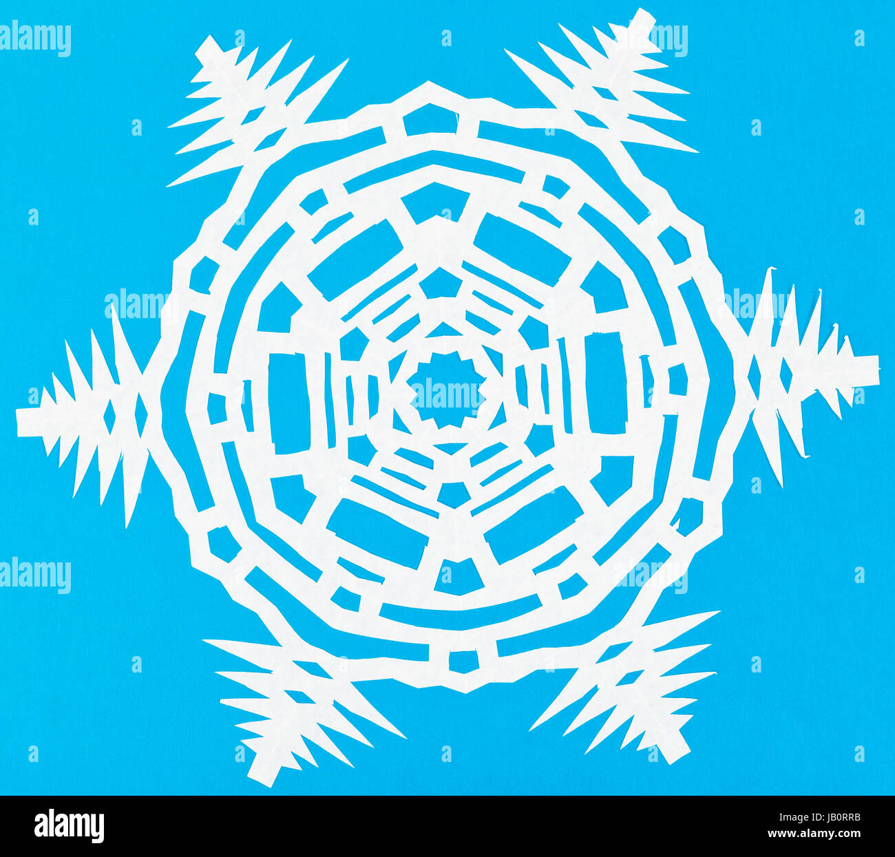 hand made cut out white snowflake on blue paper Stock Photo - Alamy