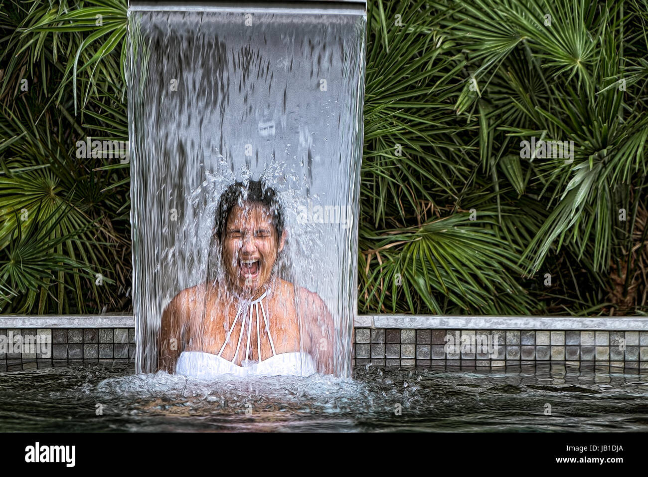 MONTARGIL/PORTUGAL 24 AUG 2016 Young girl under water fall in a swimming pool Stock Photo