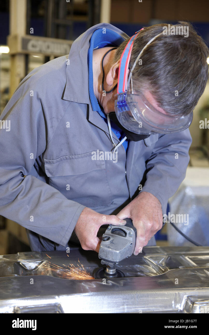 factory floor worker using a angle grinder on metal surface Stock Photo
