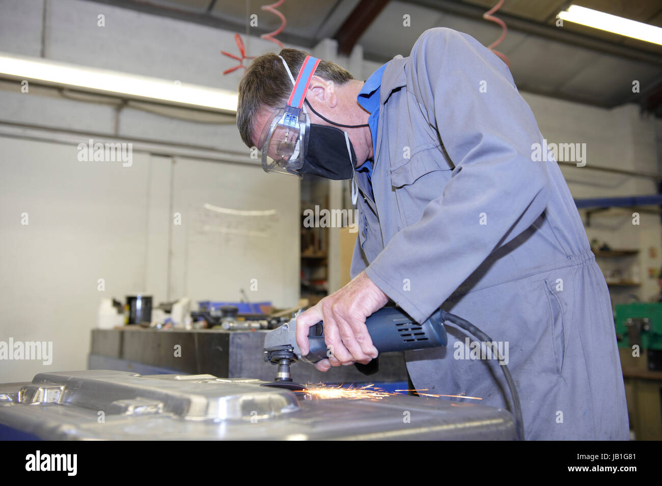 factory floor worker using a angle grinder on metal surface Stock Photo