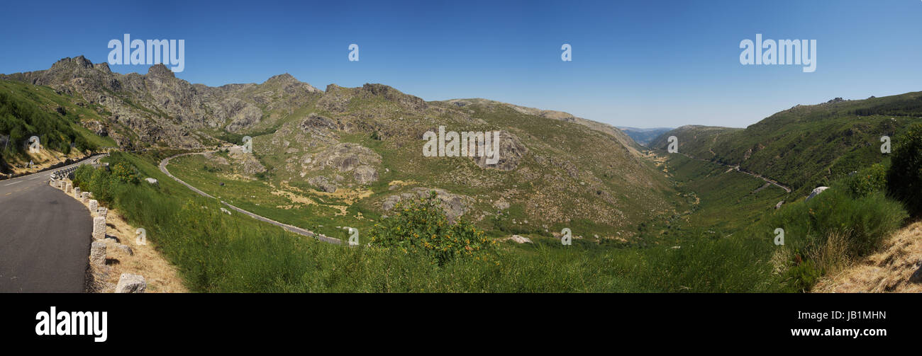 Large panorama of river Zezere glacial valley (Manteigas) and Estrela mountain range. Tarmac panoramic road winding around the mountains and slopes. S Stock Photo