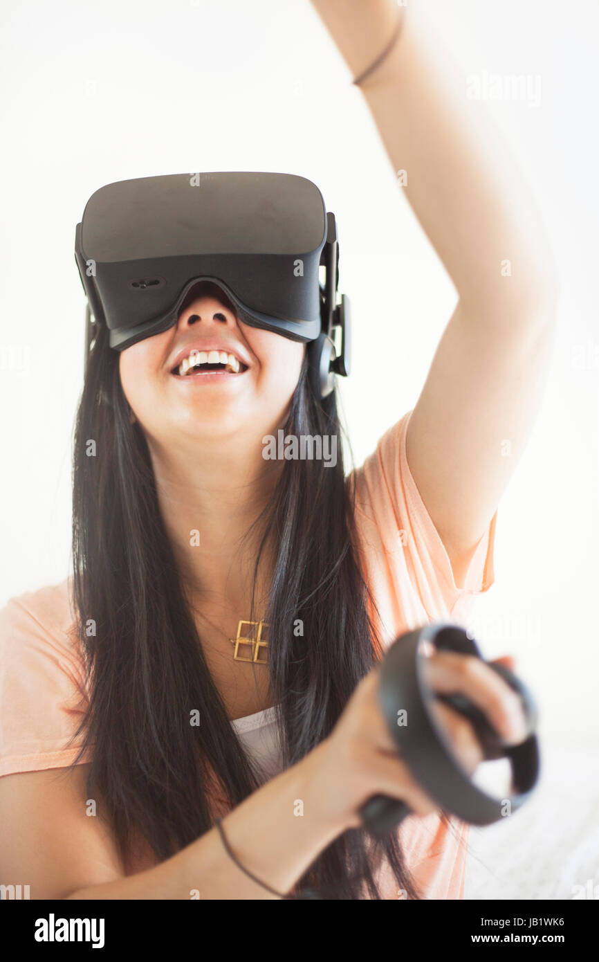 Young Asian woman wearing virtual reality headset Oculus Rift and demonstrating how to use the touch control Stock Photo