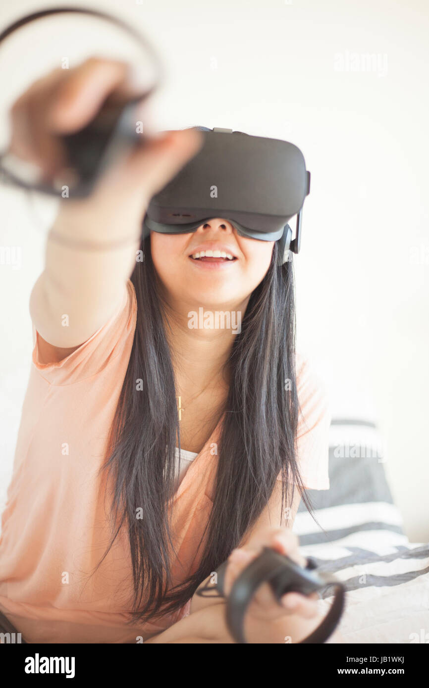 Young Asian woman wearing virtual reality headset Oculus Rift and demonstrating how to use the touch control Stock Photo