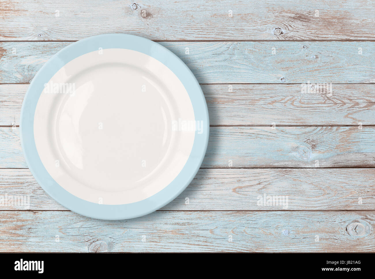 white empty dinner plate with blue border on wooden table Stock Photo