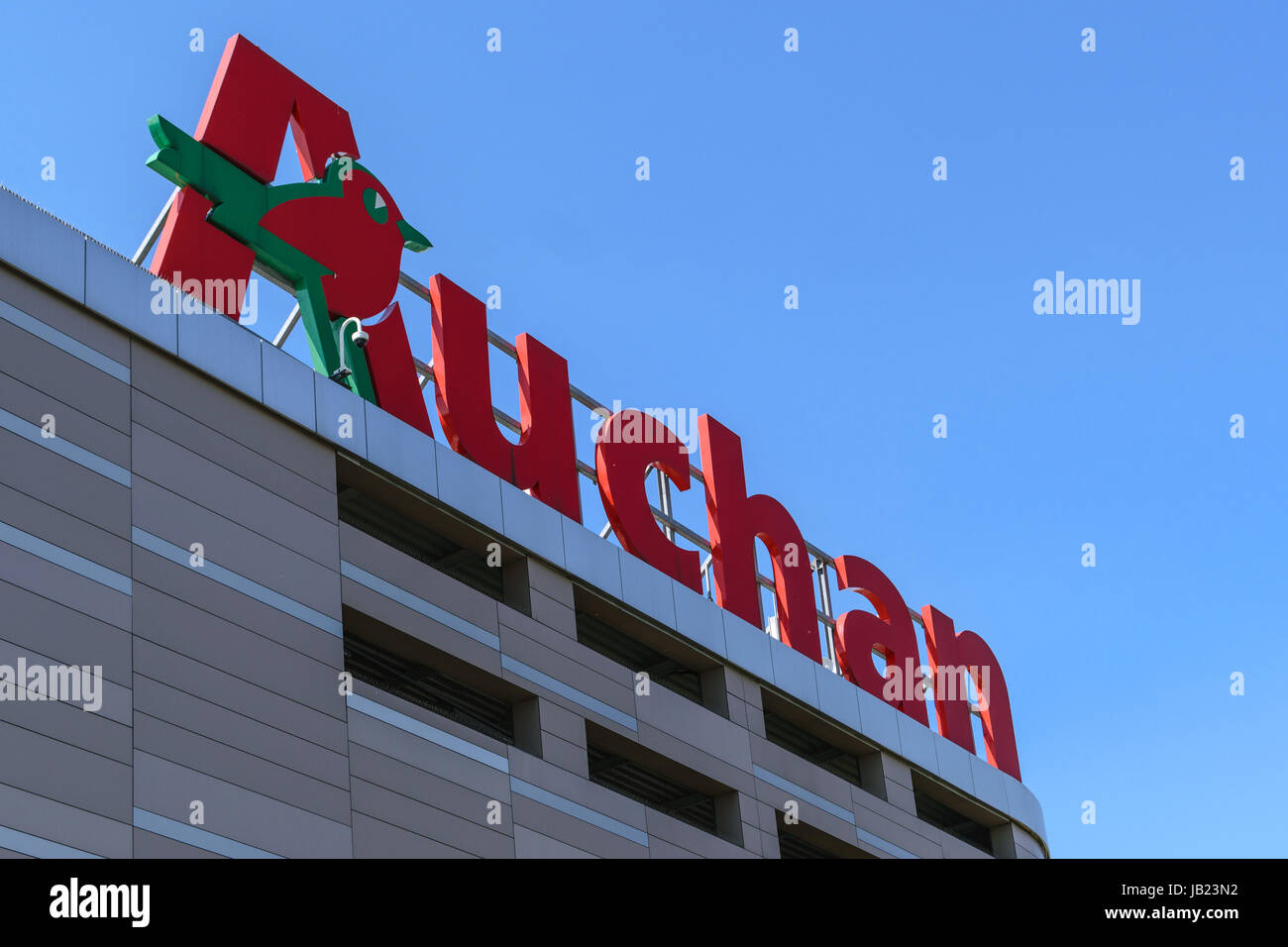 Krakow, Poland - 03 June 2017: Sign of the Auchan hypermarket on the blue sky in a sunny day. Auchan is a French international distribution hypermarke Stock Photo