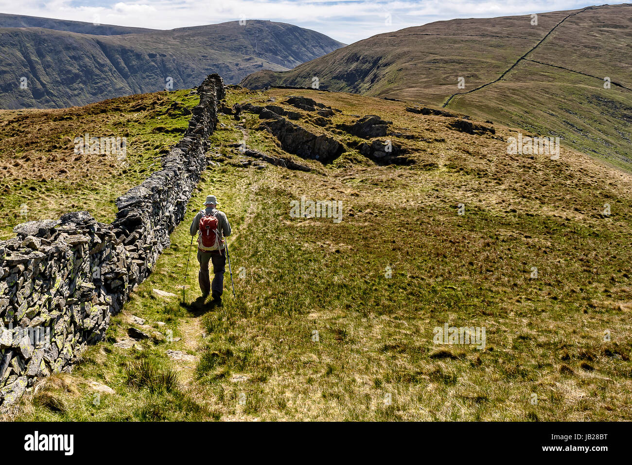 Lone walker heading across open fells of Caudale Moor in the Lake District national park Stock Photo