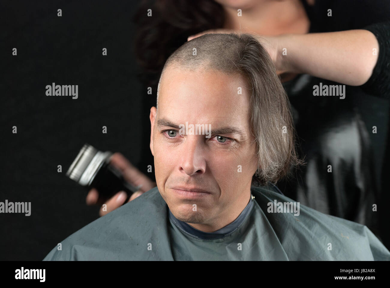 Close-up of a mourning man getting his long hair is shaved off for a cancer fundraiser. Stock Photo