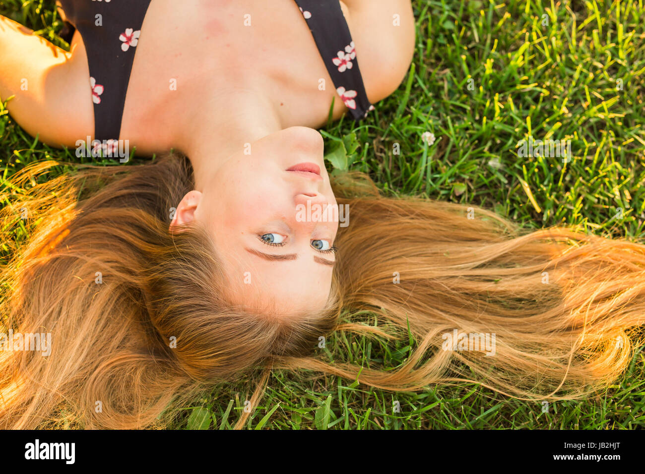 Portrait of a young woman lying on the grass Stock Photo - Alamy