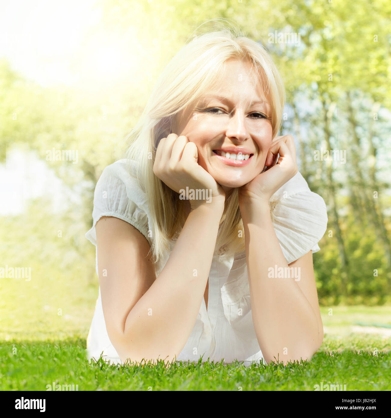 Happiness smiling blonde woman relaxing on green grass in the park ...