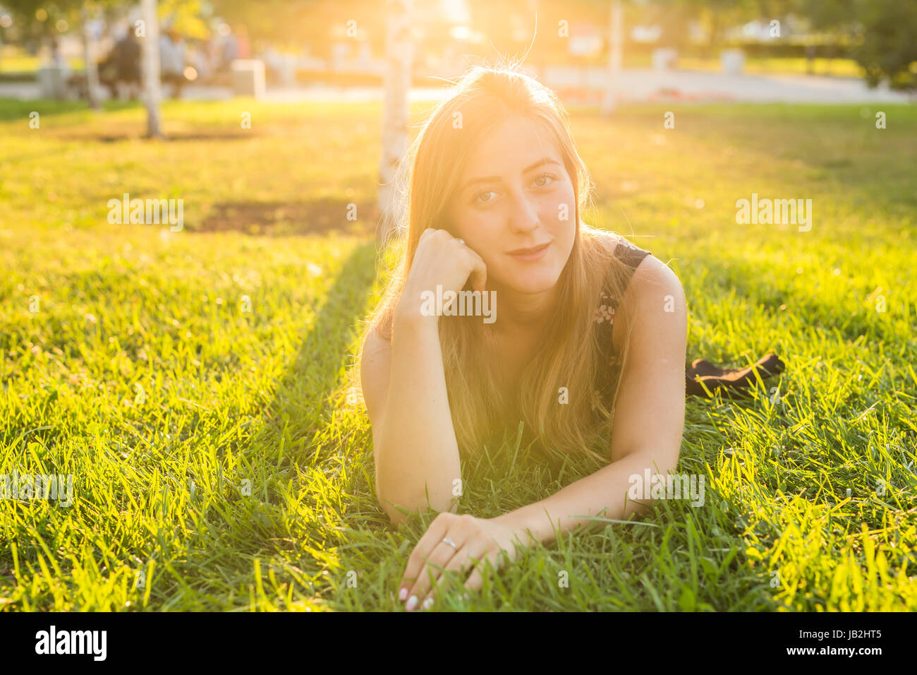Portrait of a young woman lying on the grass in sunlight Stock Photo ...