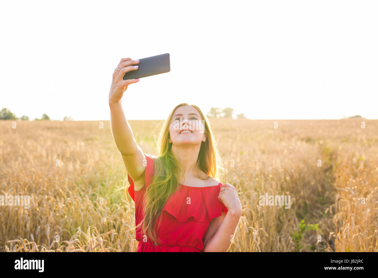 Young happy woman smiling while taking selfie picture with mobile phone ...