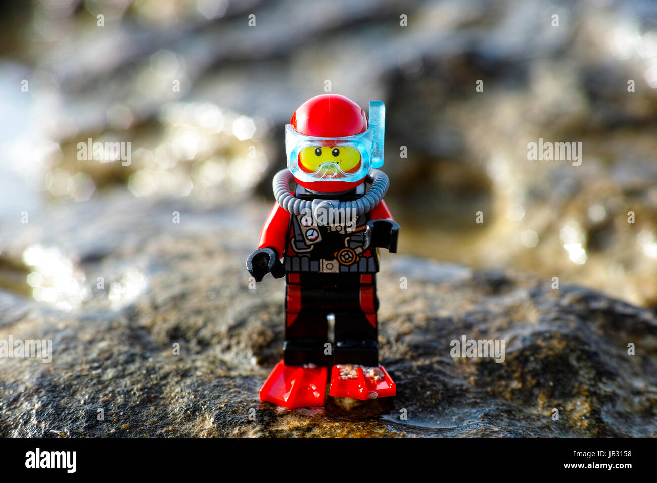 Paphos, Cyprus - October 09, 2016 Lego scuba diver minifigure standing on stone in sea. Stock Photo