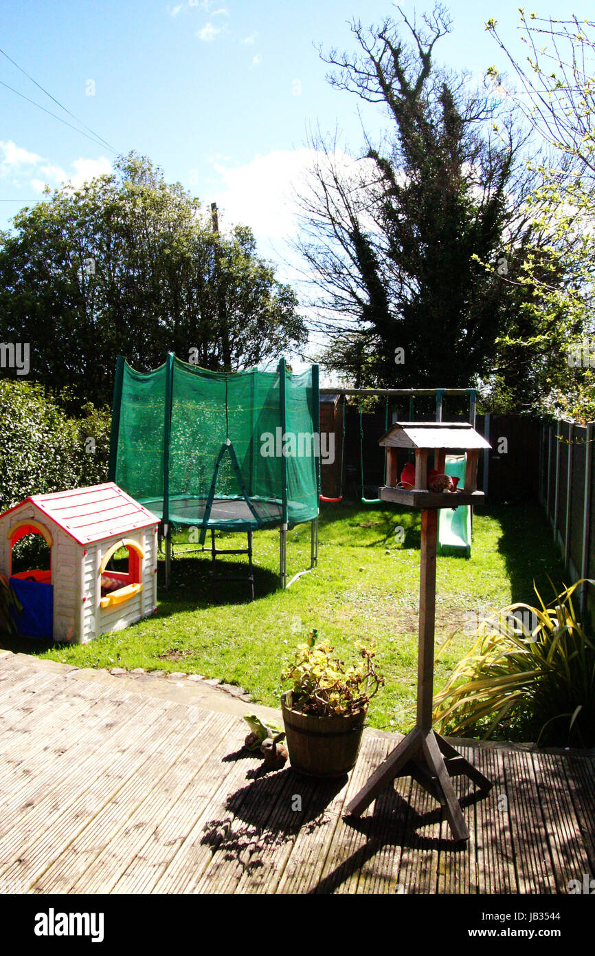 A backgarden with a trampoline,playhouse, swings, slides, birdhouse and fences Stock Photo
