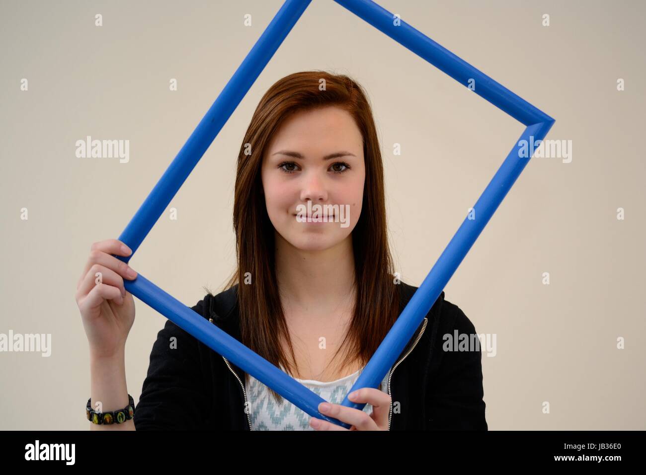 Teenager schaut zufrieden durch blauen Bilderrahmen Stock Photo