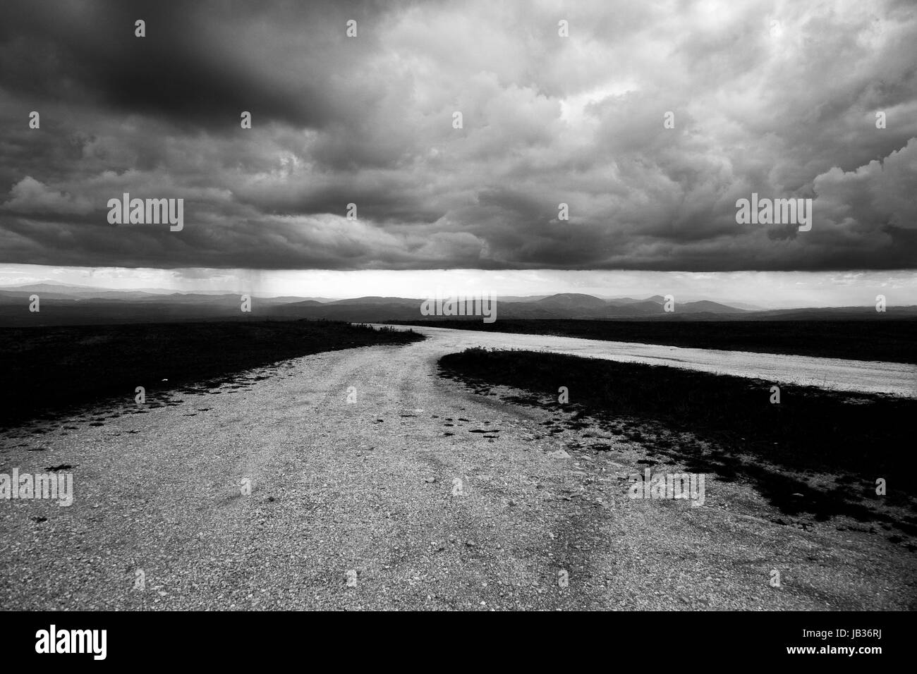 A view of a mountain road with a very low and menacing rooftop of clouds Stock Photo