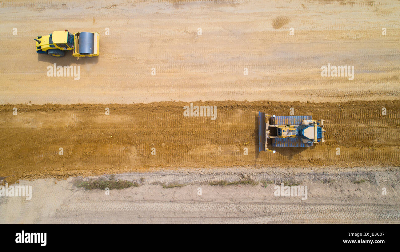 Aerial shot of a backhoe loader and a steamroller on a roadwork near Vue, Loire Atlantique, France Stock Photo