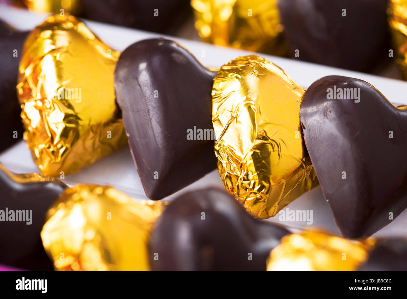 Chocolate hearts, some wrapped in gold foil, close up Stock Photo Alamy