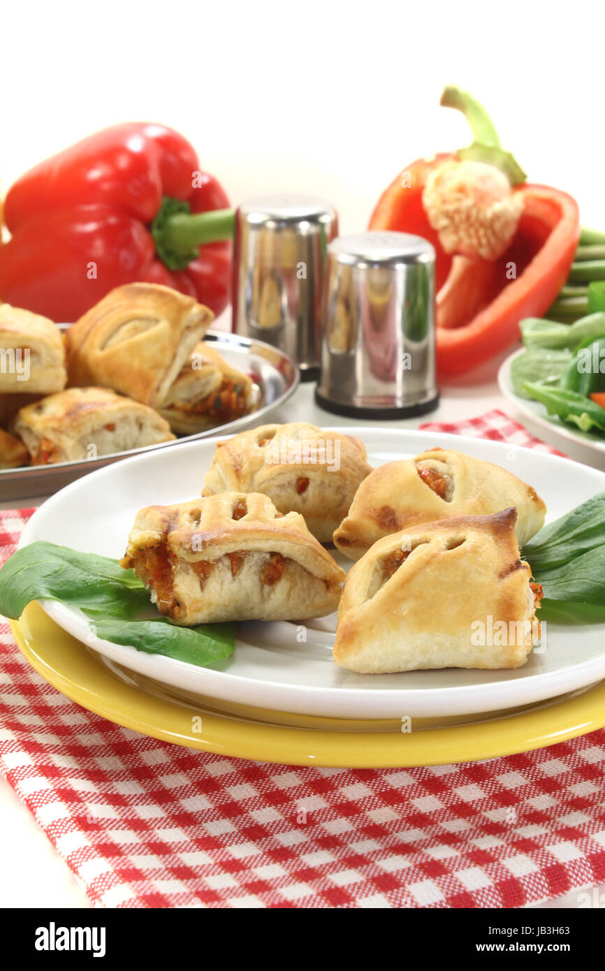 Blätterteigtaschen mit Paprika und Käsefüllung vor hellem Hintergrund Stock Photo