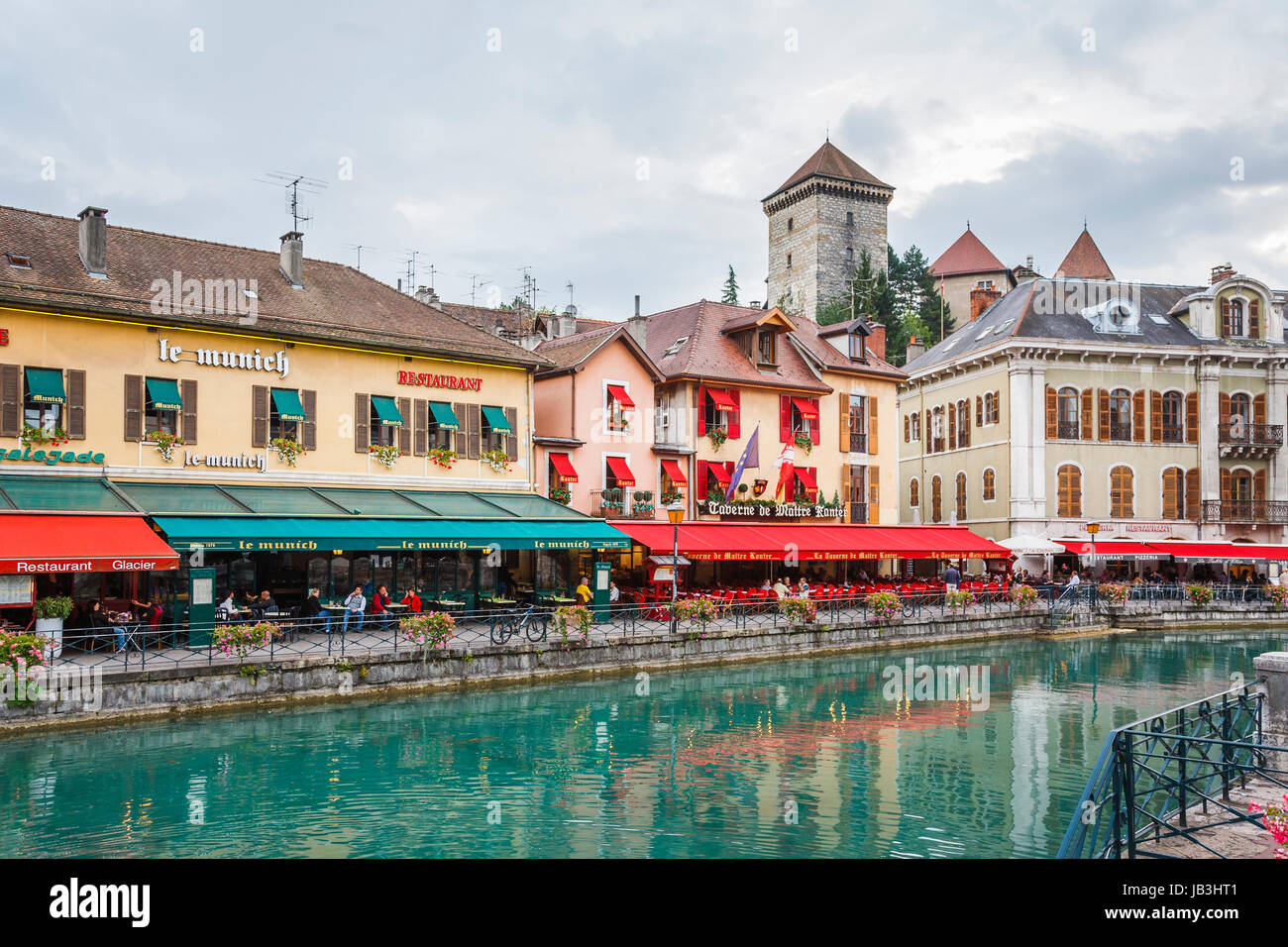 Restaurants and cafes with colourful red and green awnings in historic buildings along the bank of the Thiou river in the old town of Annecy, France Stock Photo