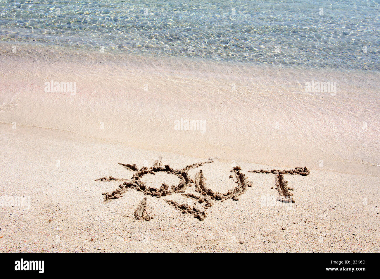 Word "OUT" written on sand on a beautiful beach, blue waves in background Stock Photo