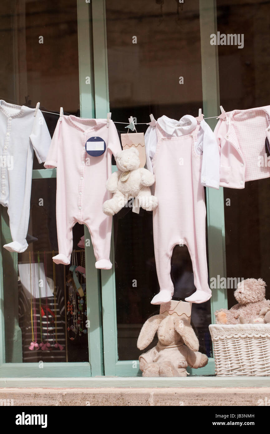 kleine baby strampler auf der wäscheleine im schaufenster kindermode geschäft dekoration Stock Photo