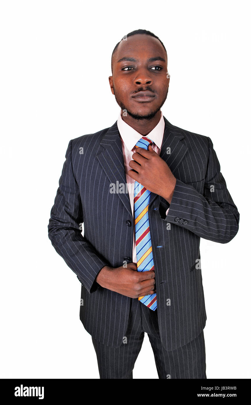 A young black business man standing in a suit and tie, fixing his tie ...