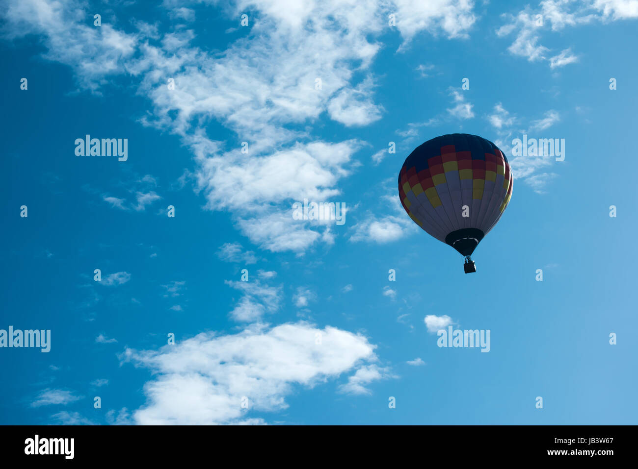 Multicolored Balloon in the blue cloudy sky Stock Photo - Alamy