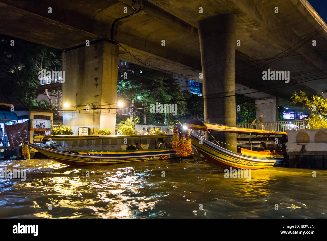 BANGKOK - NOVEMBER 1, 2013 - Boat captains tie their longtail tourist boats for the night under a bridge on Chao Phraya River in Bangkok circa November 2013. Stock Photo