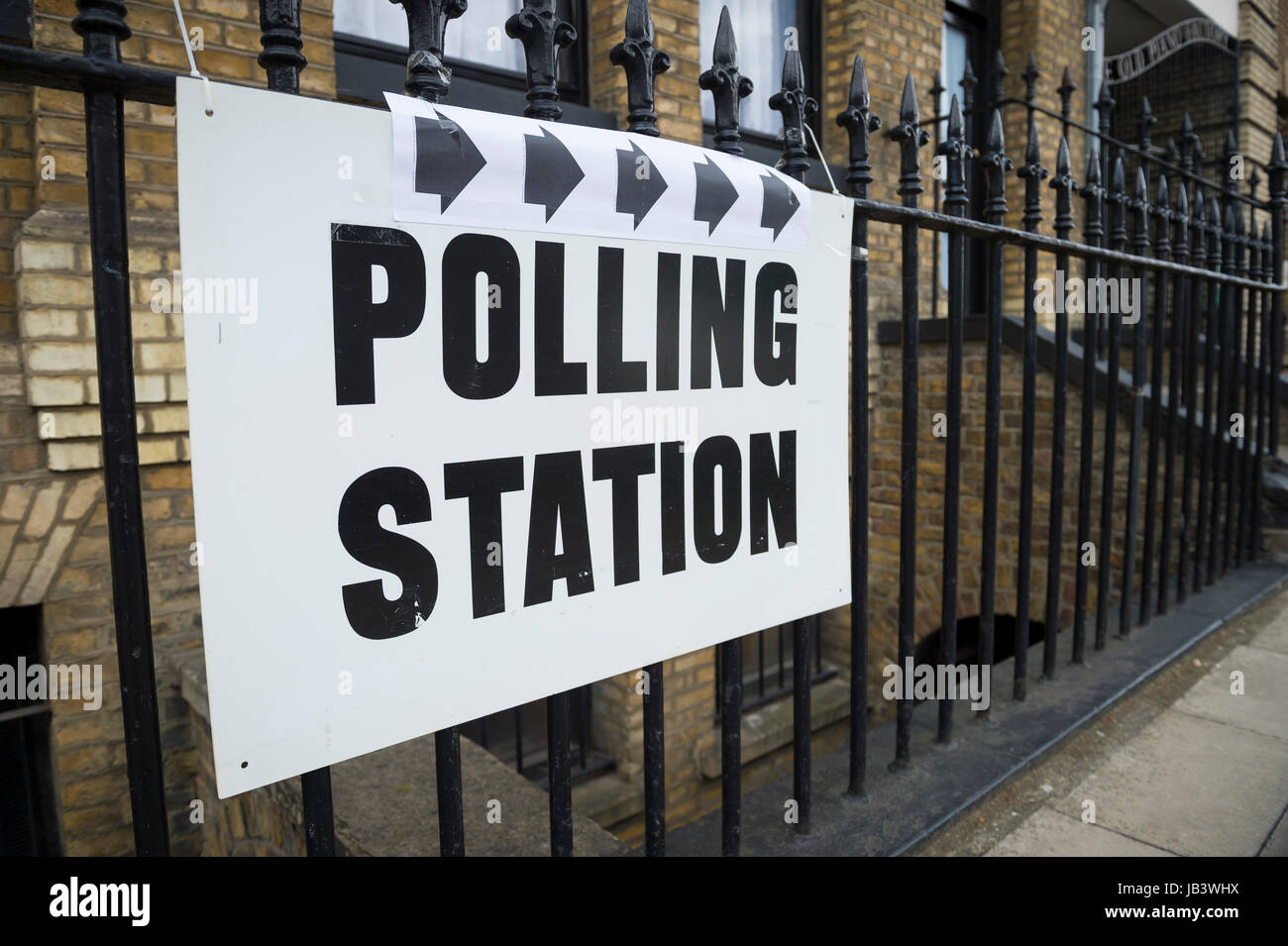 British election polling station sign hanging on gate post next to a green hedge in the UK Stock Photo