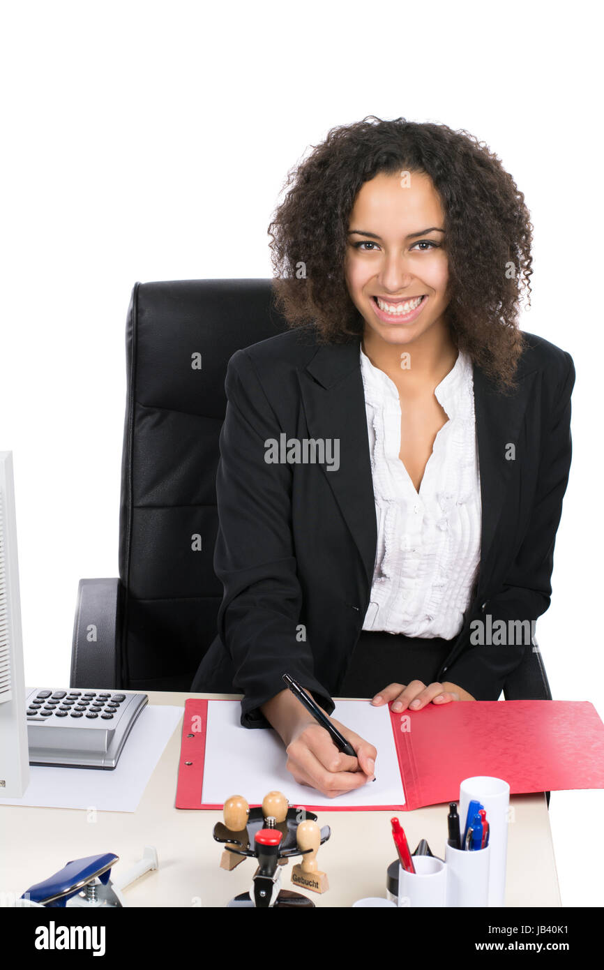 Junge, hübsche Angestellte sitzt am Schreibtisch im Büro und schreibt in eine Mappe Stock Photo