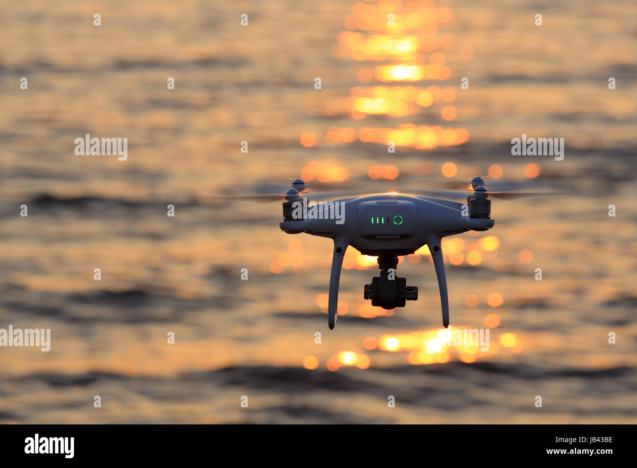 Remote controlled drone flying in air and sparkle sunlight on sea Stock