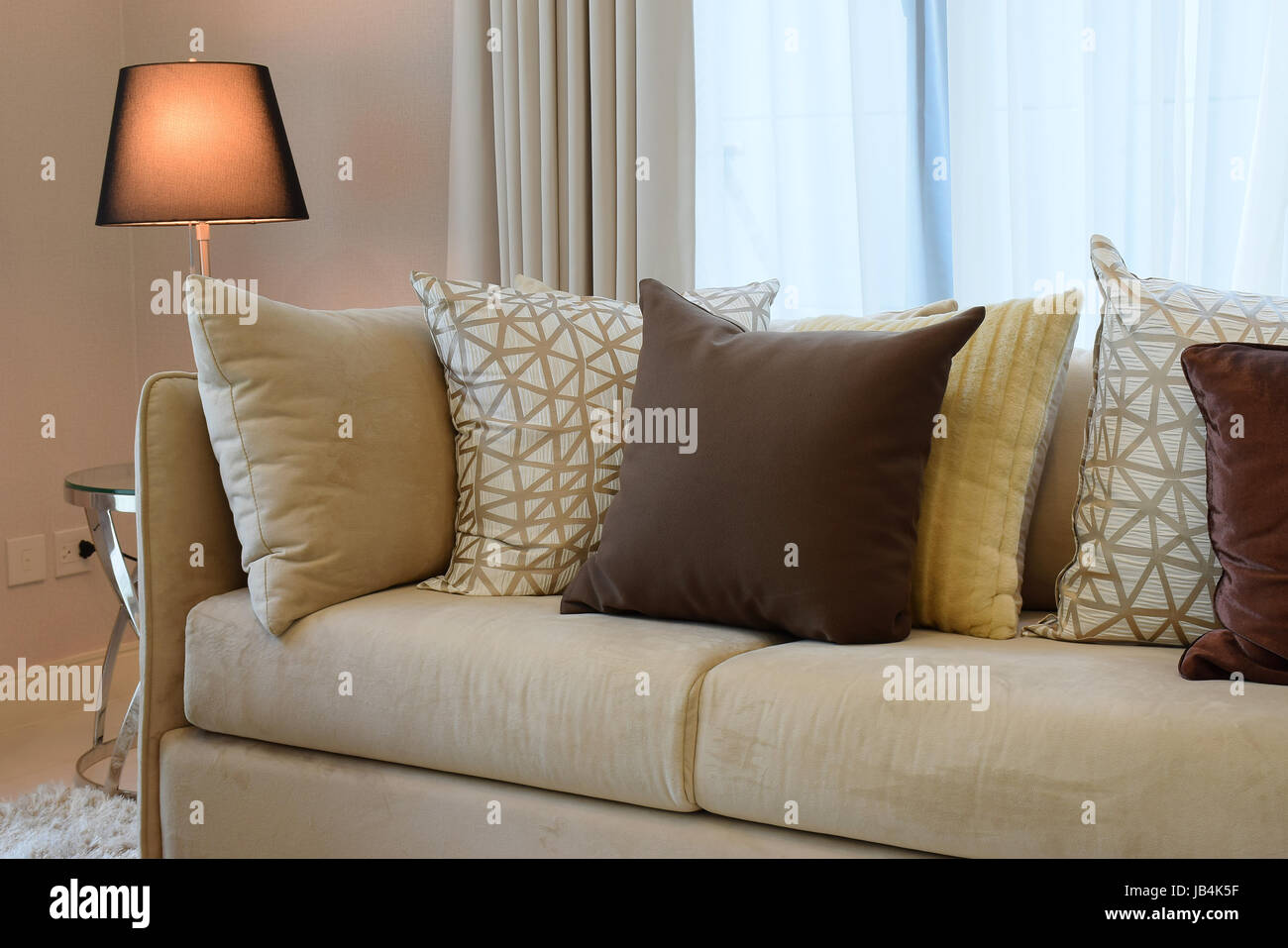 Sturdy brown tweed sofa with grey patterned pillows and lamp Stock Photo