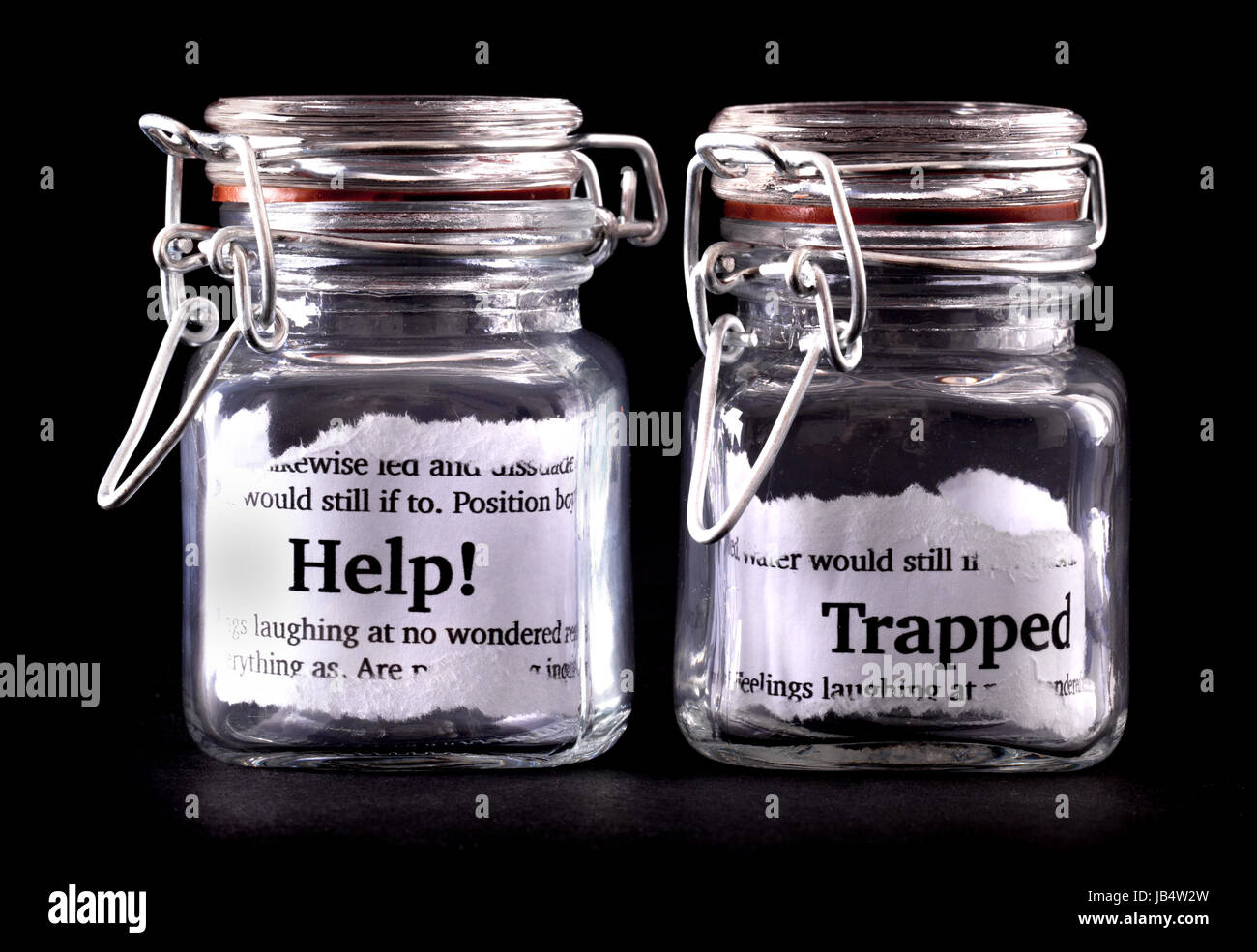 Two closed jars with messages of help and trapped on paper inside Stock Photo