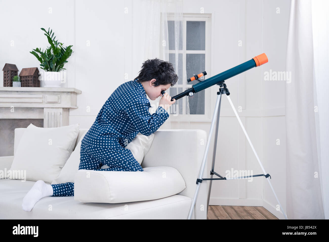 side view of focused little boy looking through telescope Stock Photo ...