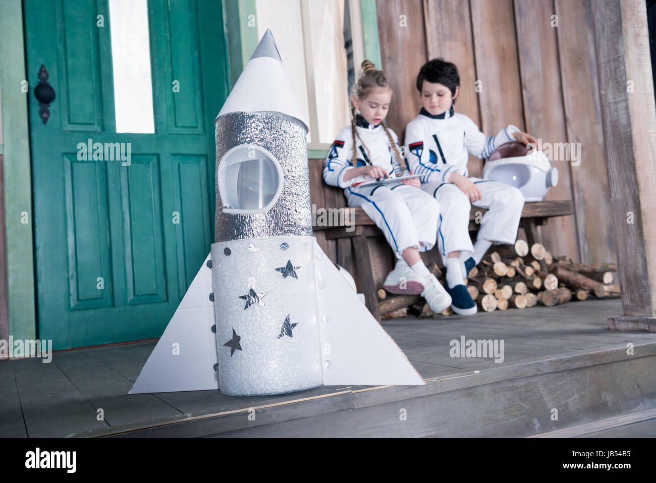 toy rocket and children astronauts behind using digital tablet Stock Photo