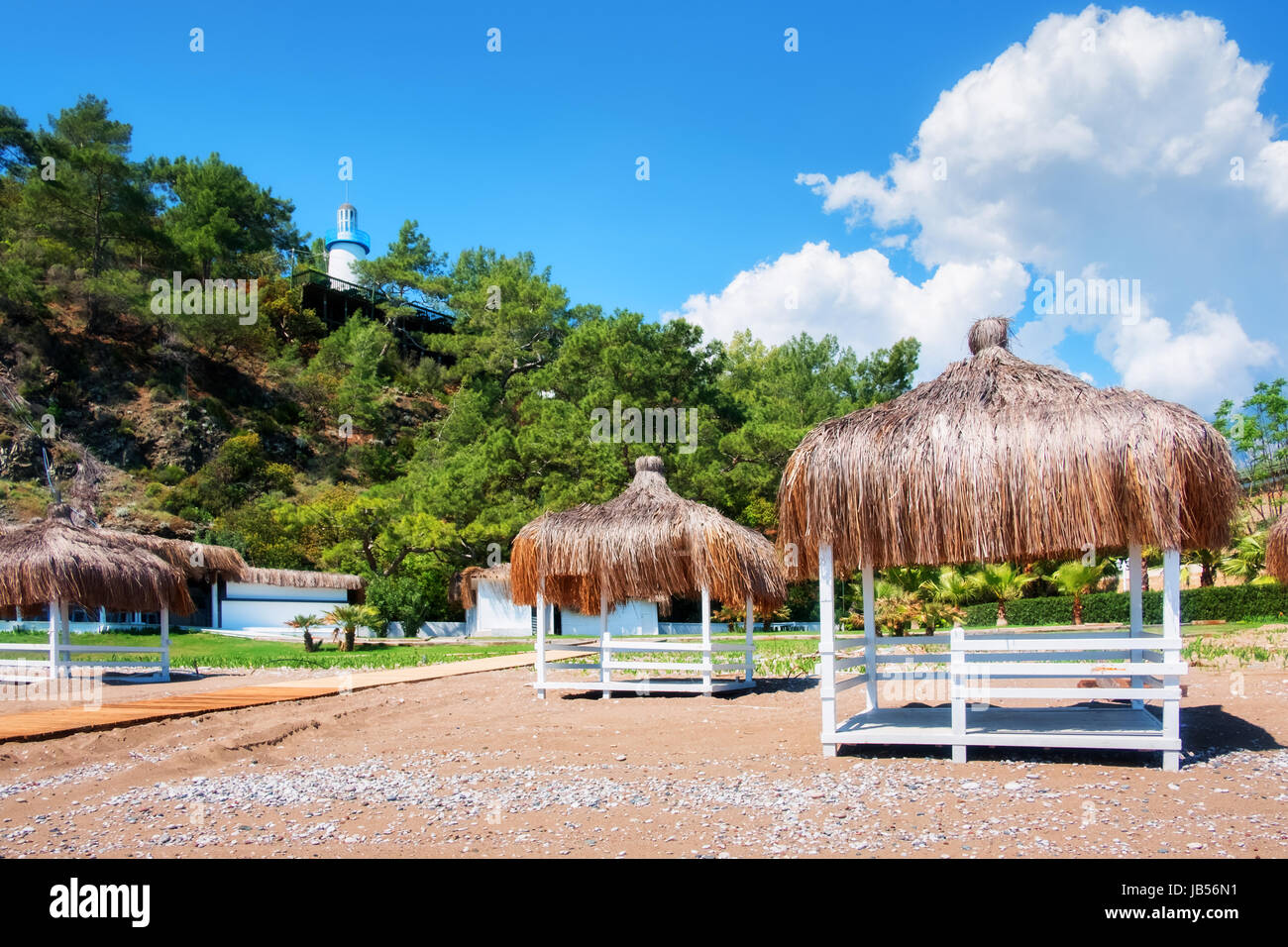 Summer arbors on beach. Breathtaking view on mediterranean sea. White wooden summerhouses on sunny day. Blue sky and fluffy clouds Stock Photo