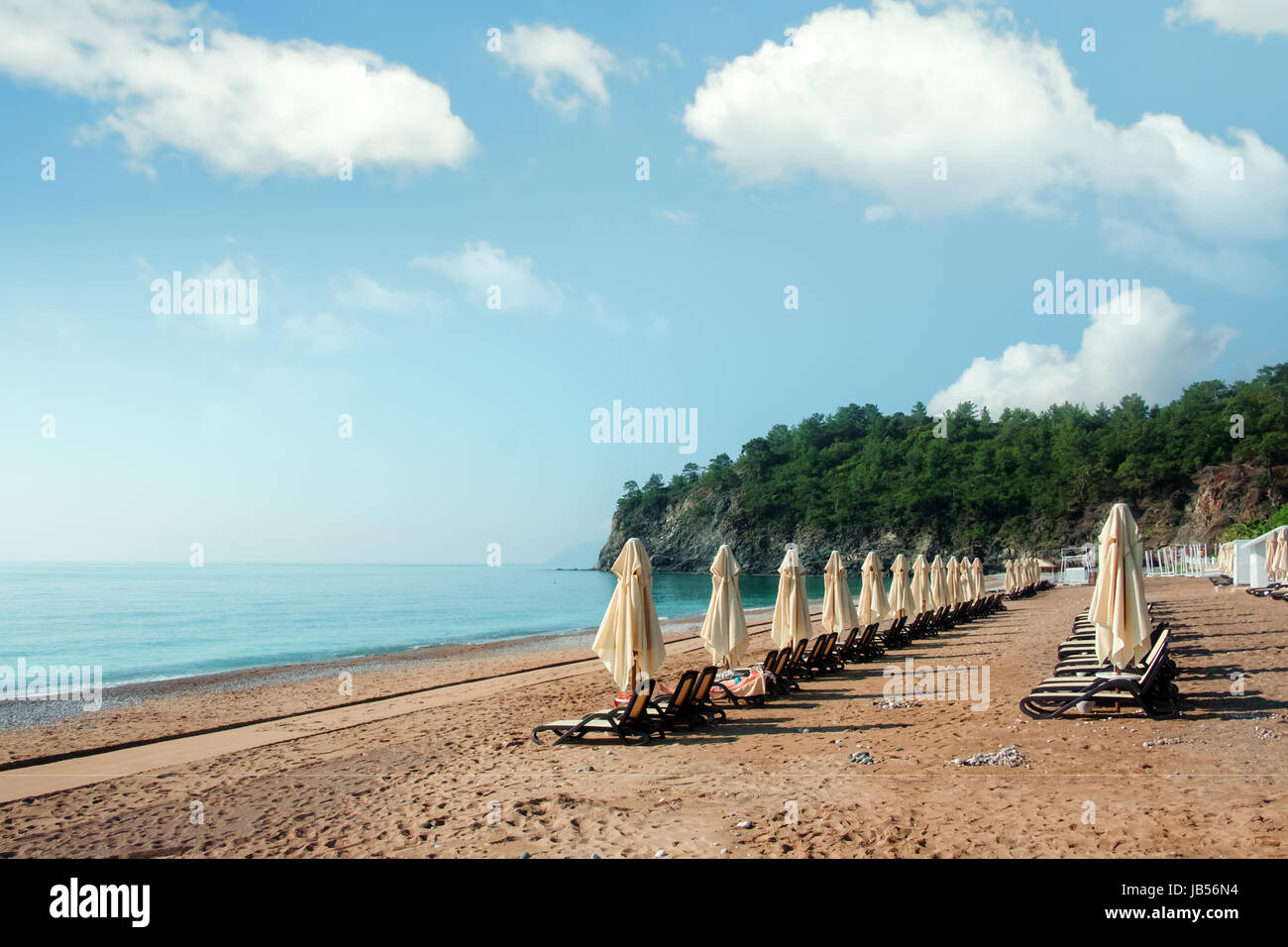 Row of sunshade umbrellas on sea beach. Tranquil view of the Mediterranean sea. Amazing pink sunrise with clear sky. Location place: Turkey, Kemer. Stock Photo