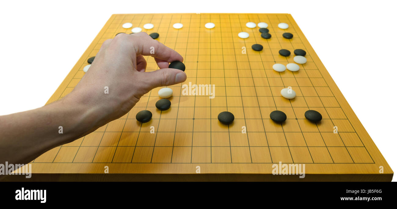 A hand placing a stone on a go board. Go is a traditional asian board game.  It is supposed to be one of the oldest games in the world Stock Photo -