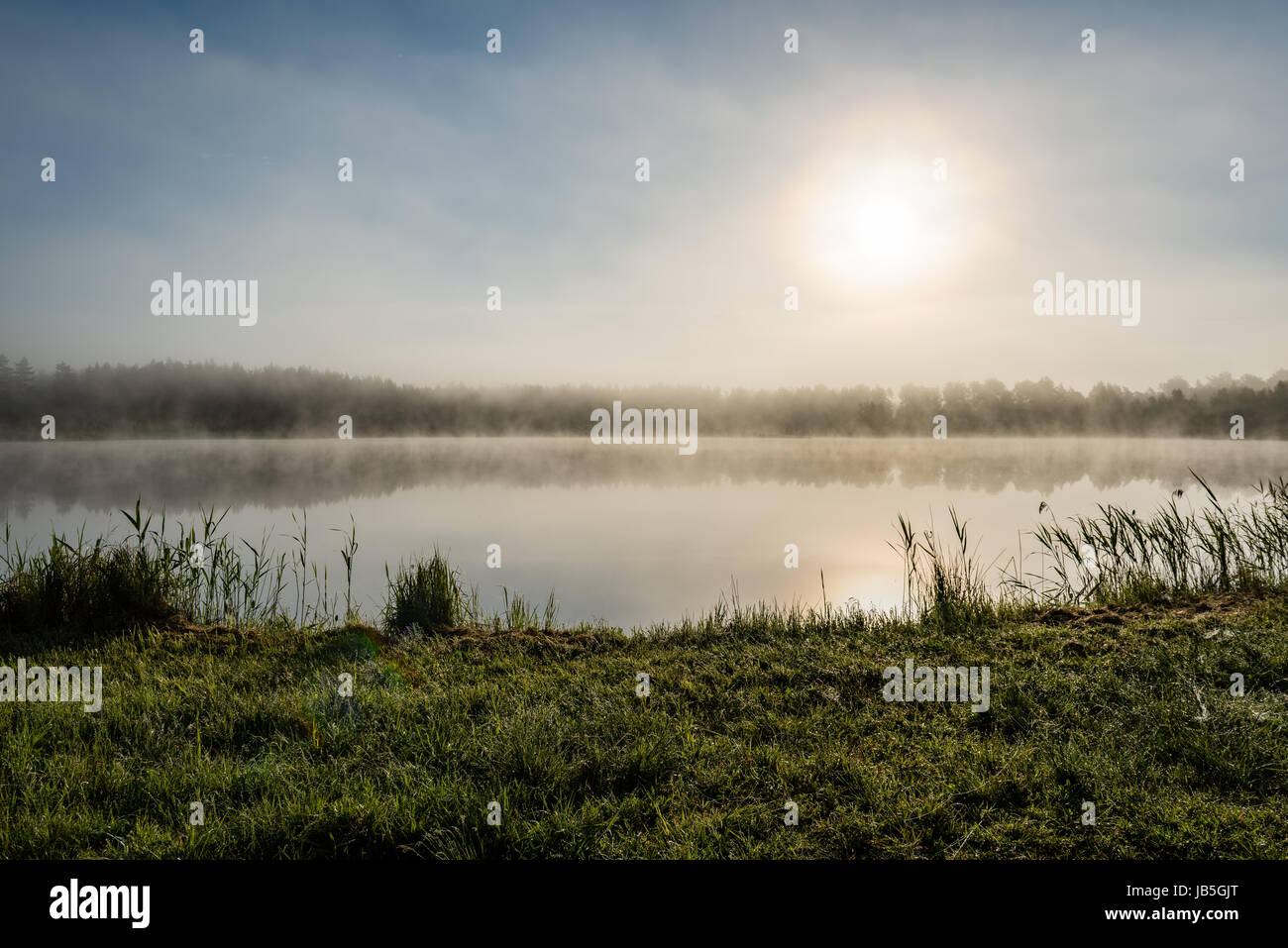 reflections in the lake water at sunrise with morning mist over the ...