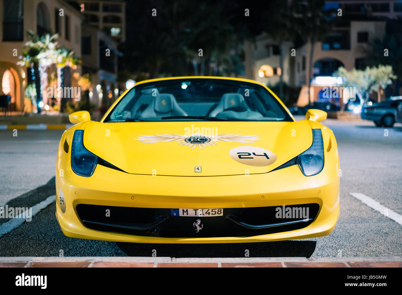 Yellow Ferrari parked outside during night time in California in the harbor of a little town Stock Photo