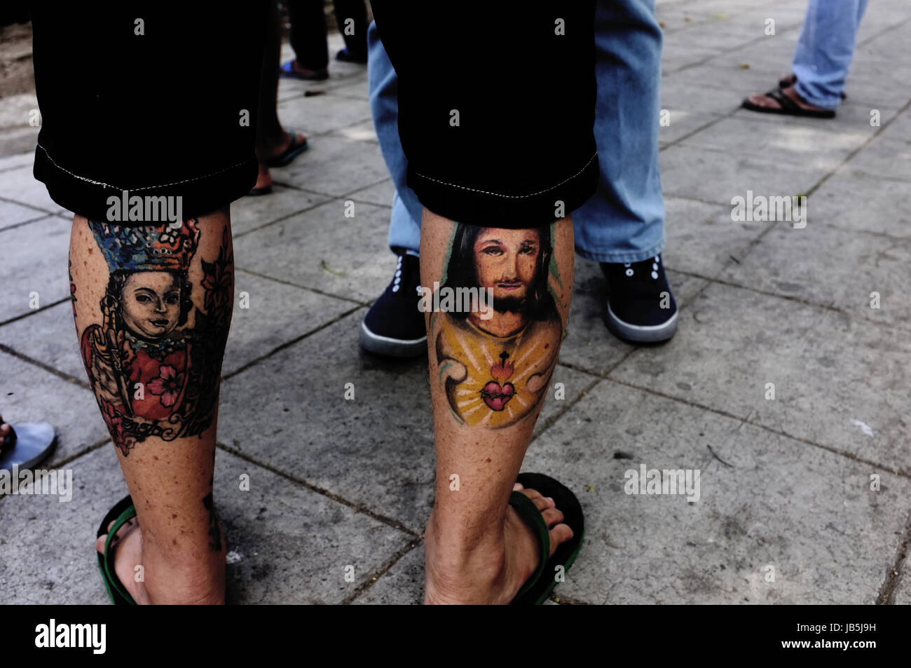 Cebu City, the Philippines - April 3, 2015. A man with Chrisitian motives tattoed on his legs is attending the Easter celebrations in Cebu City. Stock Photo