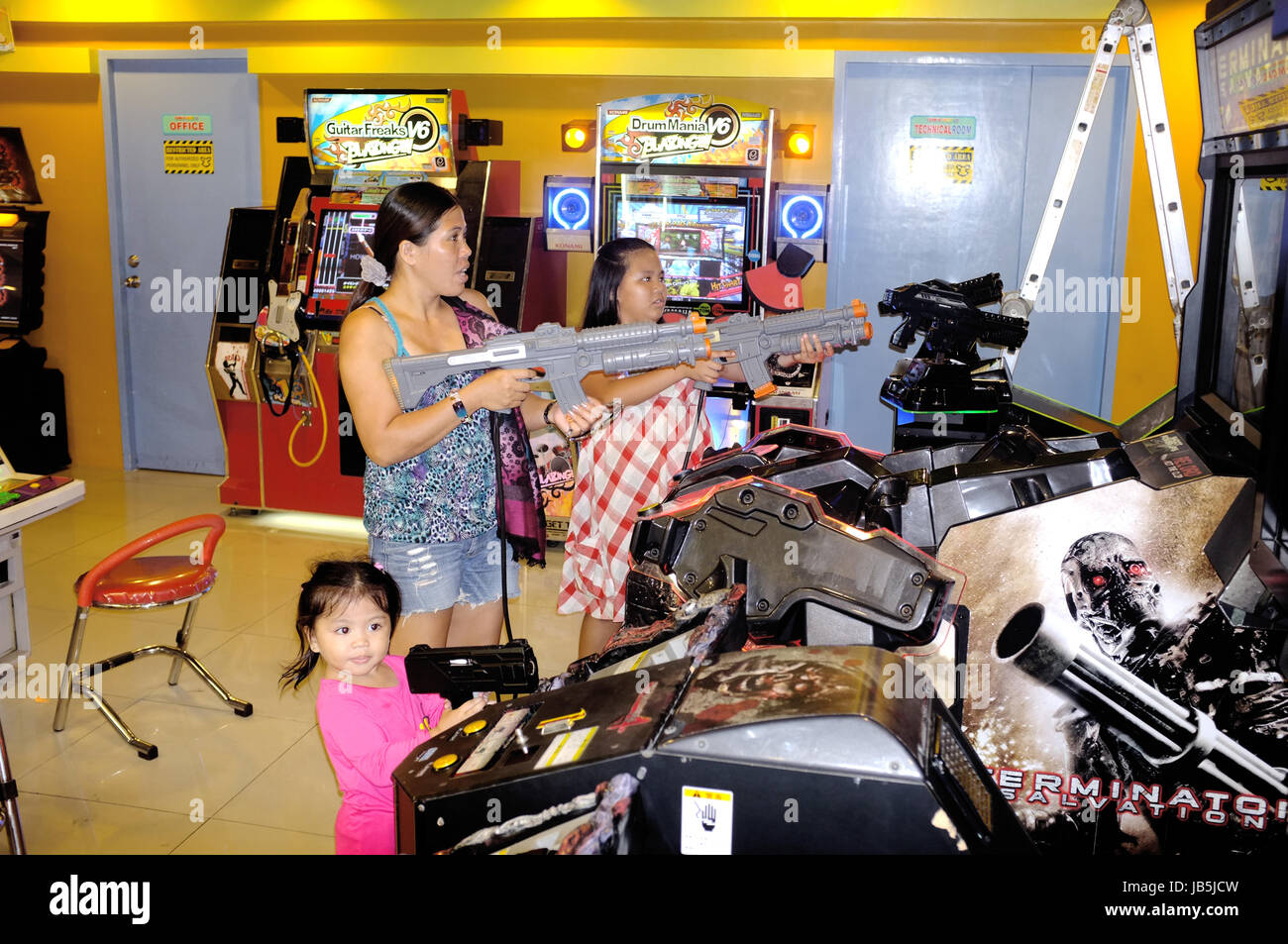 Cebu City, the Philippines - March 26, 2015. Mother and daughter are playing shooting games in an arcade hall in Cebu City. Stock Photo