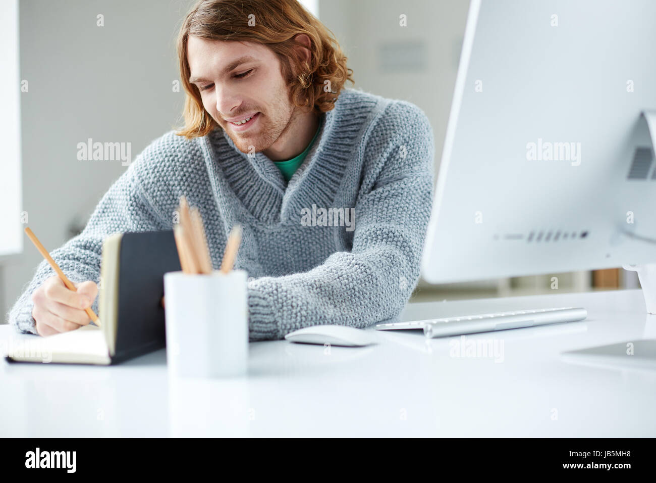 Portrait of handsome man making notes in office Stock Photo - Alamy