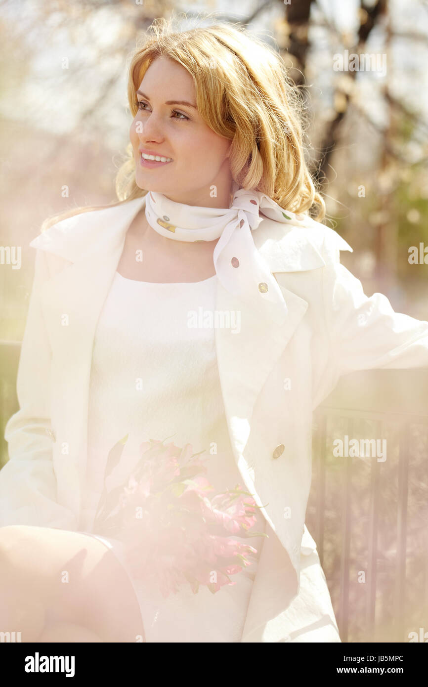 Portrait of a young woman sitting on bench in park Stock Photo - Alamy