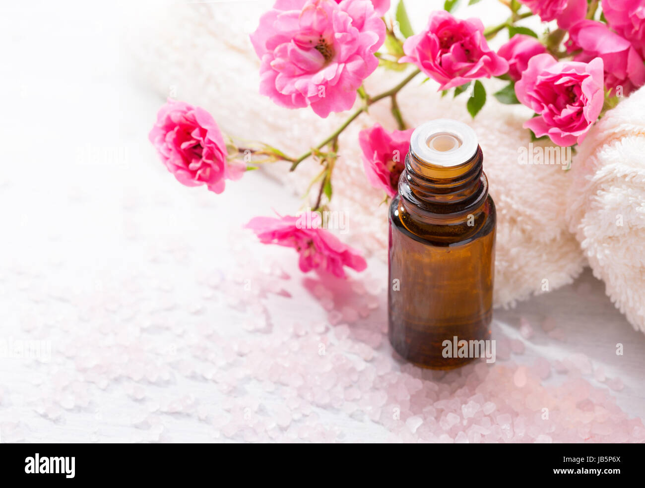 Essential oil, Mineral bath salts,  branch  of  small pink  rose  on the wooden table. Stock Photo