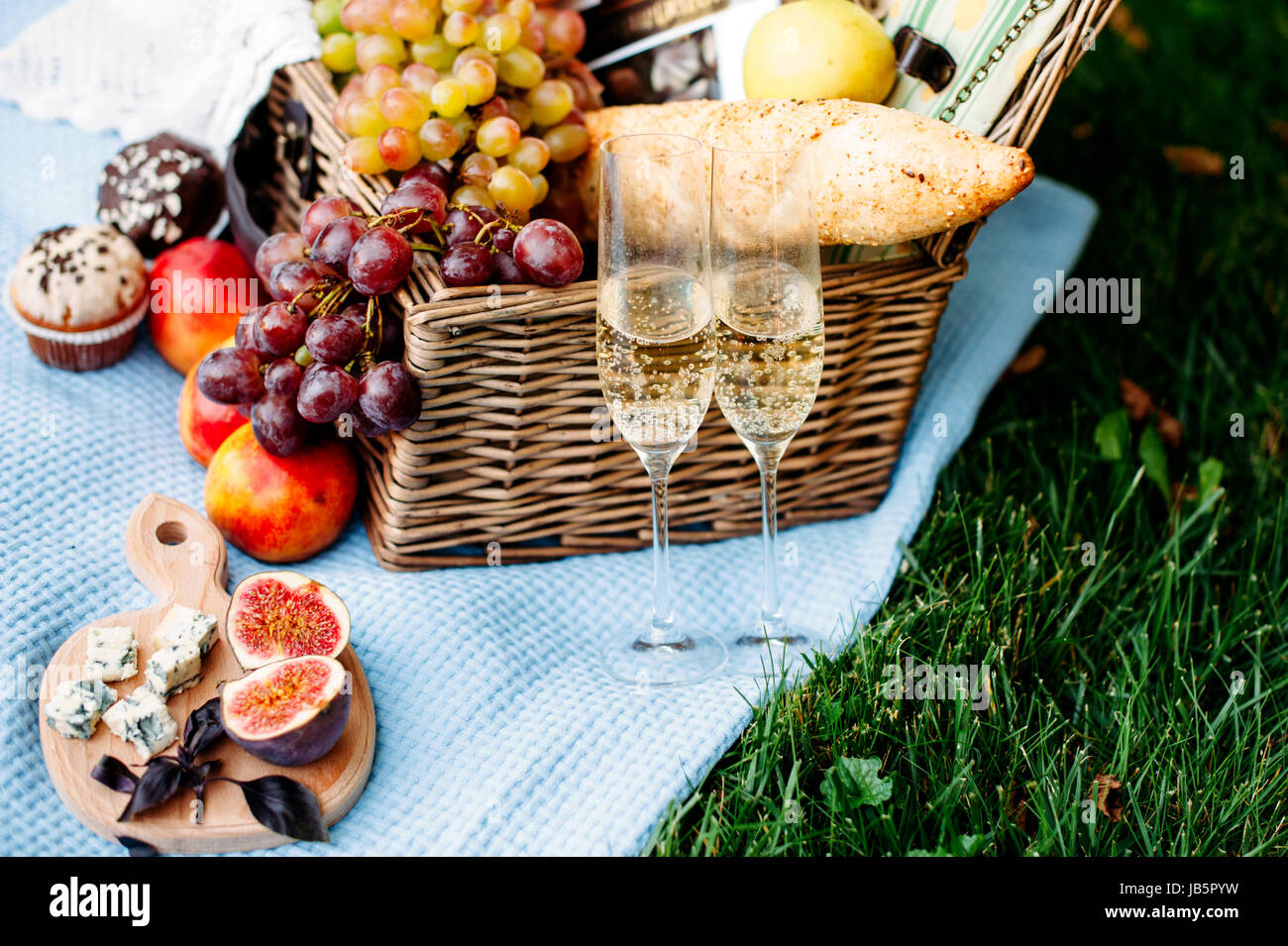 Picnic at the park on a grass, delicious food basket, wine, grapes