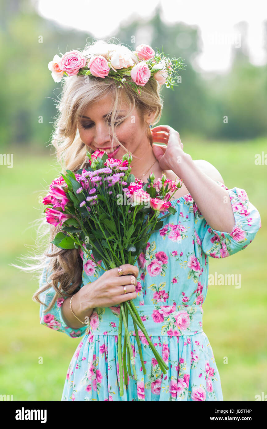Beautiful blonde girl holding bouquet of flowers at the countryside ...
