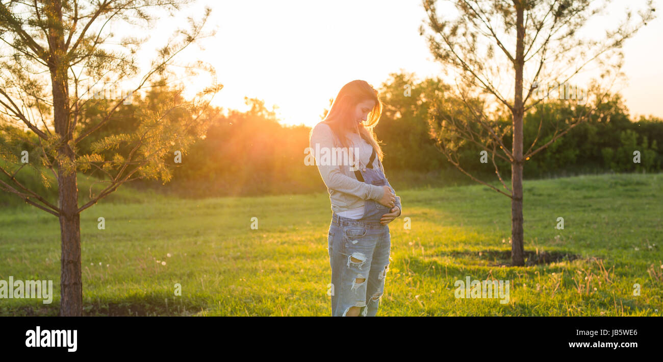 Pregnant young woman hugging her stomach outdoors Stock Photo - Alamy