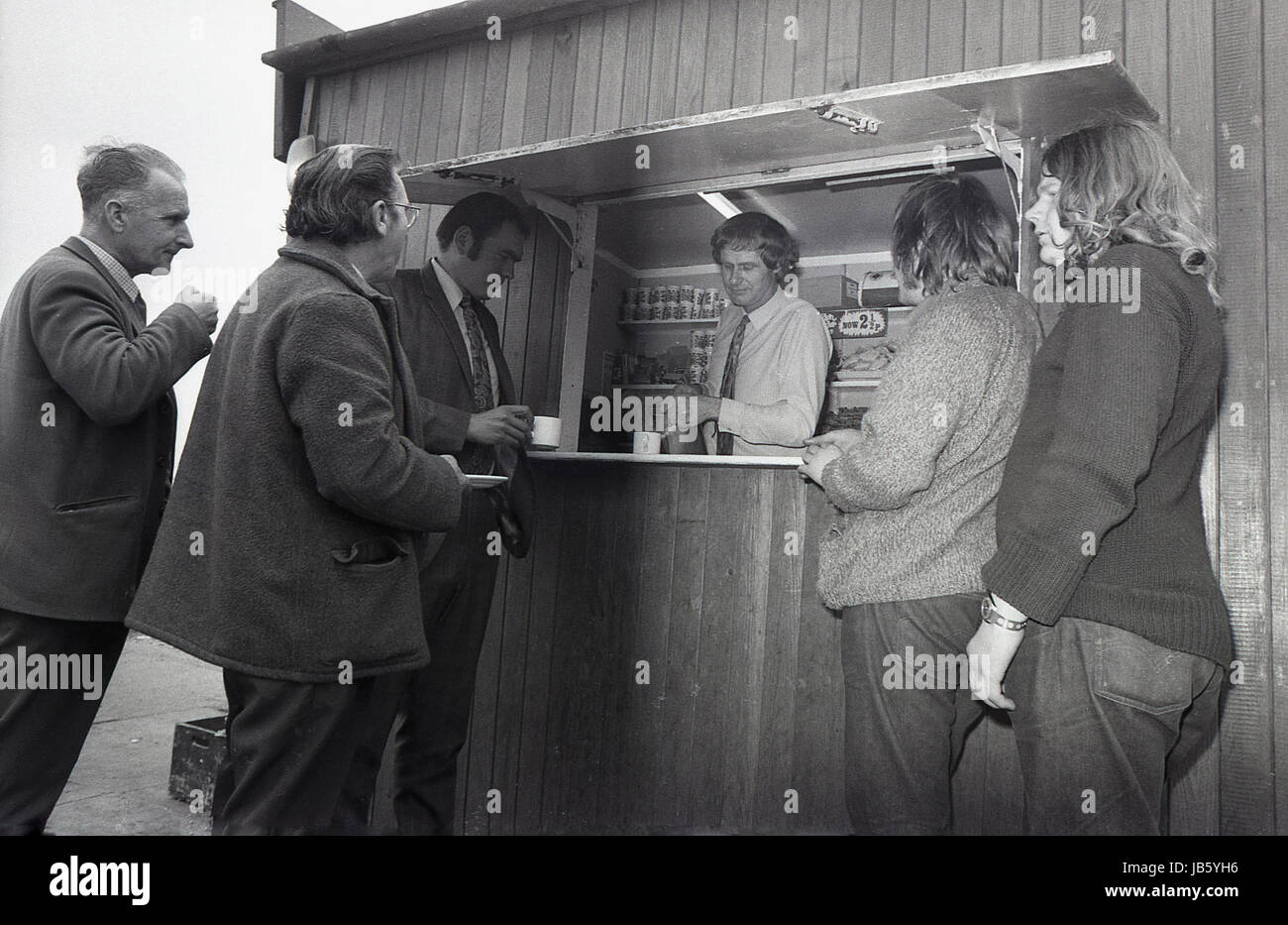 1973, historical picture, customers standing at the counter outside the famous Blackheath Tea Hut. A simple, basic snack bar, the small wooden hut with a service hatch for light food and beverages was a well known rest stop for people travelling on the A2 road at Greenwich, South London, SE3. An opportunity for a break, a cup of tea and some social interaction on one's journey. Stock Photo